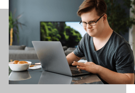 Mensch mit Down-Syndrom beim bedienen des Laptops.